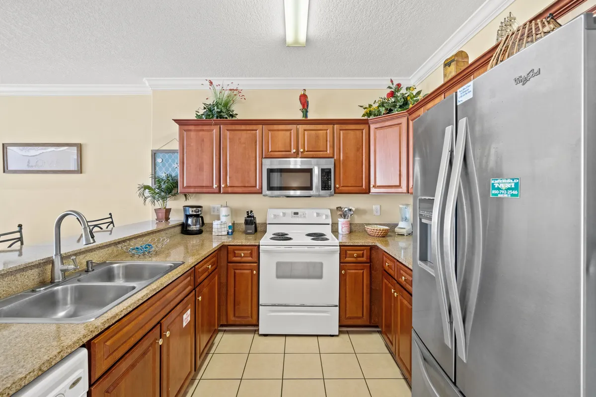 A well-lit kitchen featuring wooden cabinets, stainless steel appliances, granite countertops, and decorative plants. The scene radiates warmth and practicality, offering a glimpse of a modern, fully equipped culinary space ideal for meal preparation and gathering.
