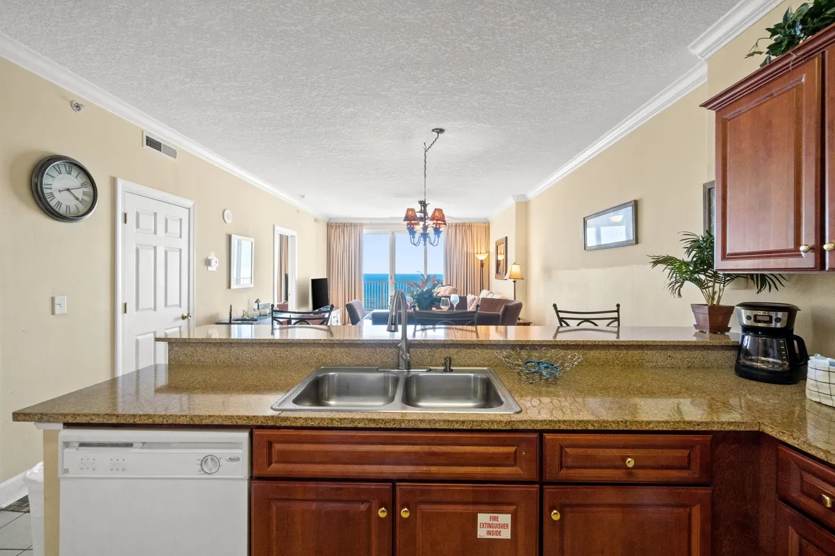 An open-plan area that combines the kitchen, dining space, and living zone. The living area features a flat-screen TV and a large window framing the ocean. The dining table and kitchen are visible, suggesting a space for gathering and easy movement between zones.